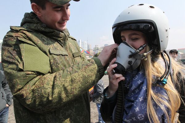سرباز در حال کمک به دختری برای پوشیدن ماسک پرواز در نمایشگاه فن آوری نظامی در میدان اصلی والی واستوک - اسپوتنیک افغانستان  