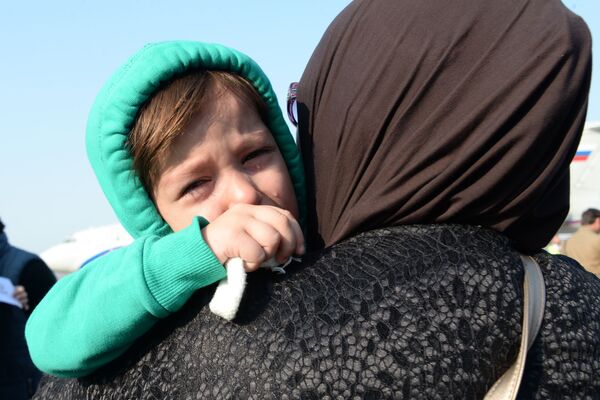 ساکنان چچن با یک کودک در دیدار از کودکان و زنان روسی که  از سوریه بازگشتند. - اسپوتنیک افغانستان  