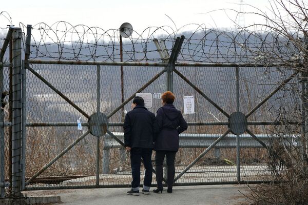 زوجی نزدیک دیوار حول منطقه ی خلع سلاح هسته ای بین کوریای شمالی و جنوبی - اسپوتنیک افغانستان  