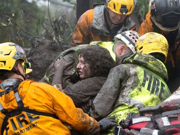 تیم نجات دهندگان یک زن را از زیر آوار خانه اش بیرون می آورند که توسط یک رانش زمین درکالیفرنیا تخریب شد - اسپوتنیک افغانستان  