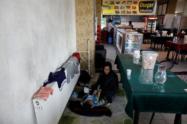 یک مادر مهاجر افغان، در حال انتظار بس در یکی از رستورانت‌های ترمینال بس در شرق ترکیه، در حال تمیز کردنی کودک‌اش - اسپوتنیک افغانستان  