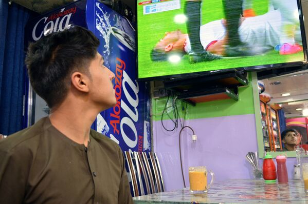 محمد کبیر، در یکی از محلات کابل دکان خوراکه فروشی دارد. او در روز نخست عید در دکان مشغول کار و تماشای همزمان جام جهانی فوتبال است. - اسپوتنیک افغانستان  