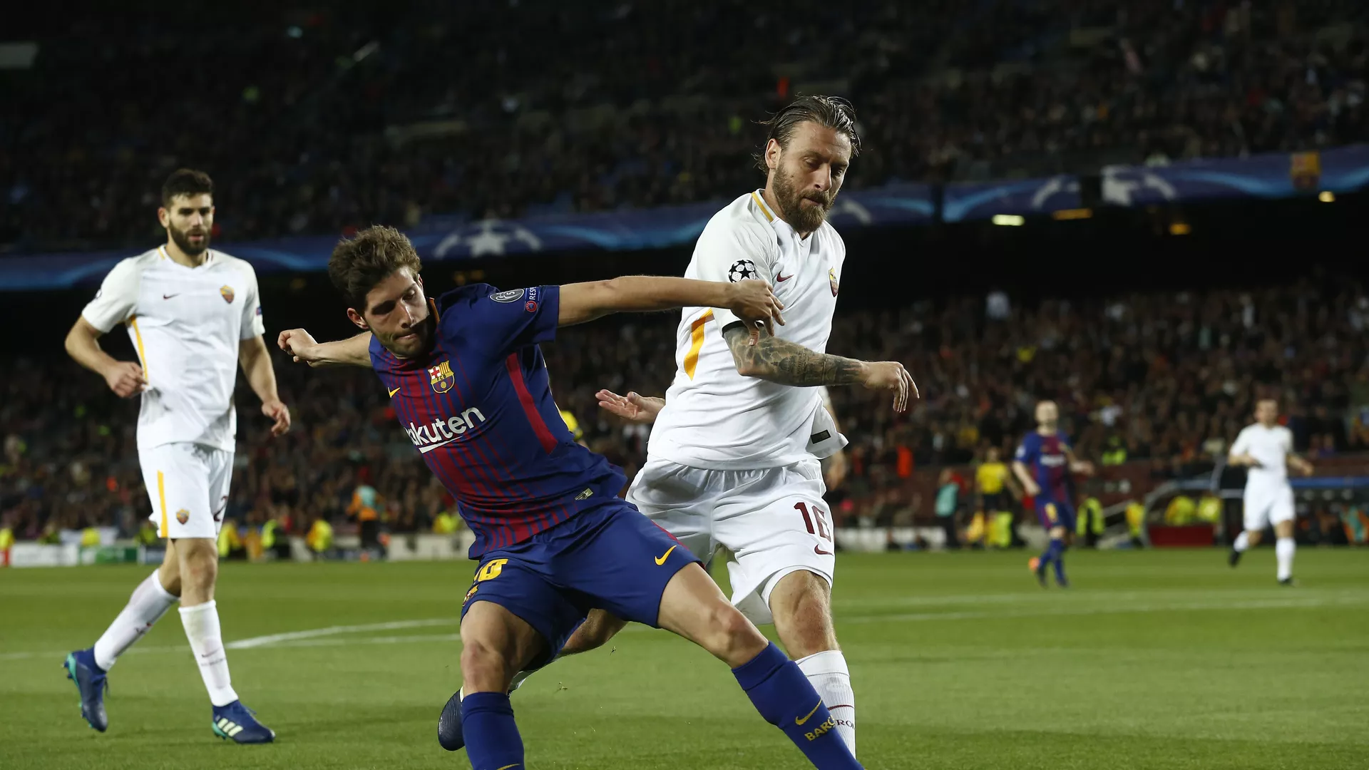 Barcelona's Sergi Roberto, left, challenges for the ball with Roma's Daniele de Rossi during a Champions League quarter-final, first leg soccer match between FC Barcelona and Roma at the Camp Nou stadium in Barcelona, Spain, Wednesday, April 4, 2018