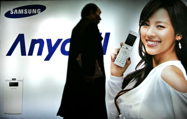 مردی در حال عبور از مقابل تخته اعلاناتی تلفون‌های همراه سامسونگ در سئول، کوریای جنوی، ۲۴ نومبر سال ۲۰۰۷ - اسپوتنیک افغانستان  