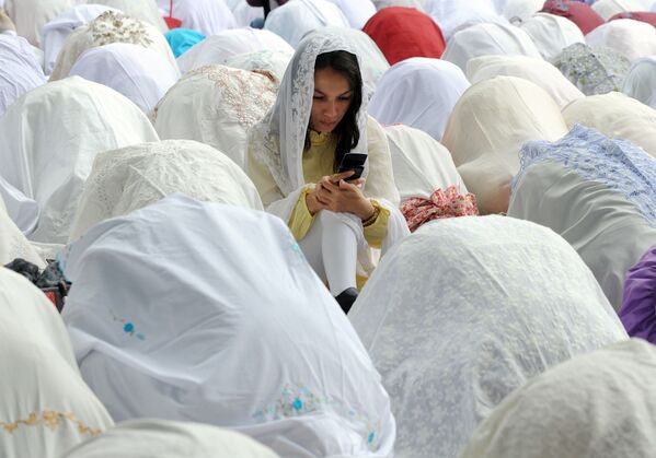 یک زن مسلمان در حال استفاده از موبایل در میان زنان نمازخوان در جاکارتا، ۶ نومبر ۲۰۱۱ - اسپوتنیک افغانستان  