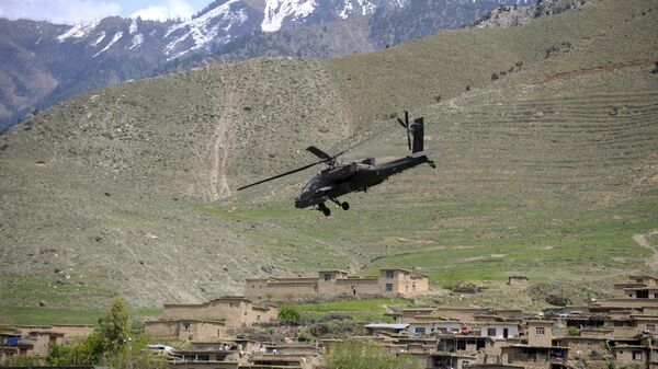 A US Army AH-64 Apache helicopter flies over a village in Naray, in Afghanistan's eastern Kunar province on April 16, 2009 - اسپوتنیک افغانستان  