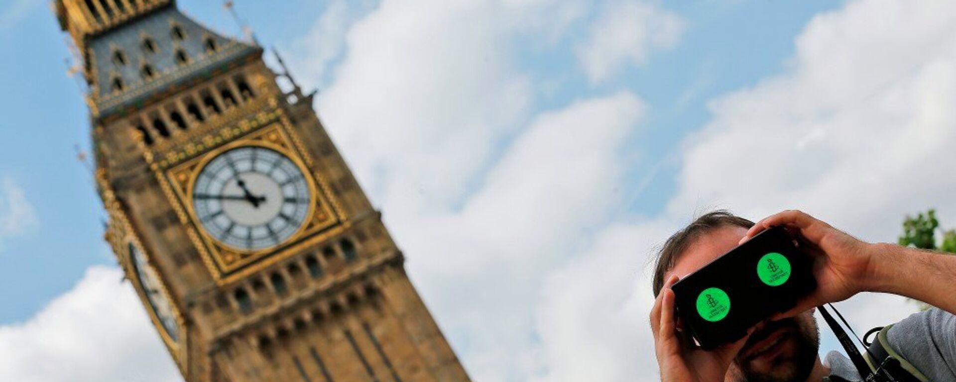 A man looks through a virtual reality device that shows a 360 degree view of the city of Aleppo, Syria during an Amnesty International protest in Parliament Square to urge the British government to do more to help Syrian refugees, London, Saturday, July 11, 2015. - اسپوتنیک افغانستان  , 1920, 05.11.2022