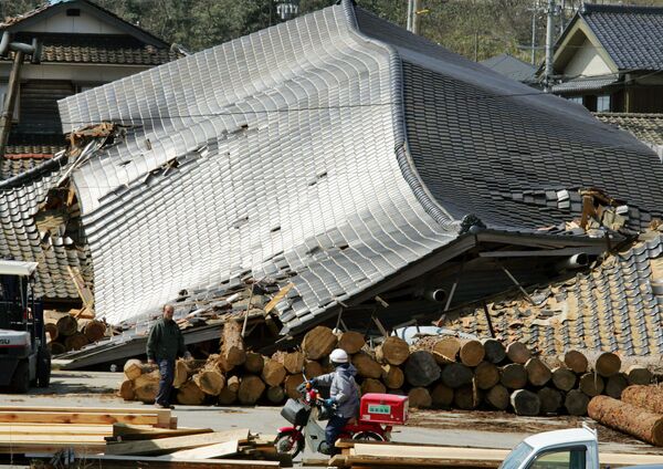  پست چی جاپانی در کنار ساختمانی در وادزیمه که در اثر زلزله واژگون شده است - اسپوتنیک افغانستان  