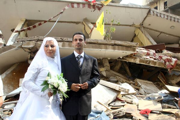عکس یک زوج جوان در زمینه ساختمان ویران پس از بمباران در حومه بیروت . - اسپوتنیک افغانستان  
