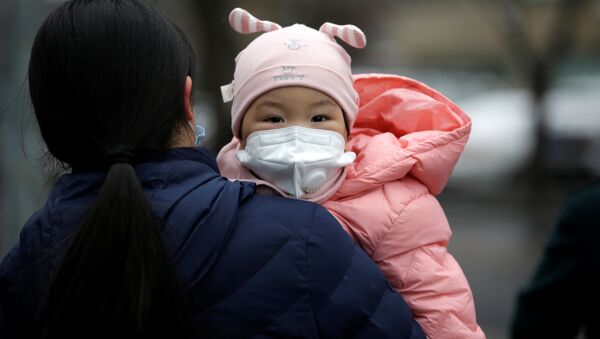 Женщина с ребенком в медицинских масках на одной из улиц Пекина - اسپوتنیک افغانستان  