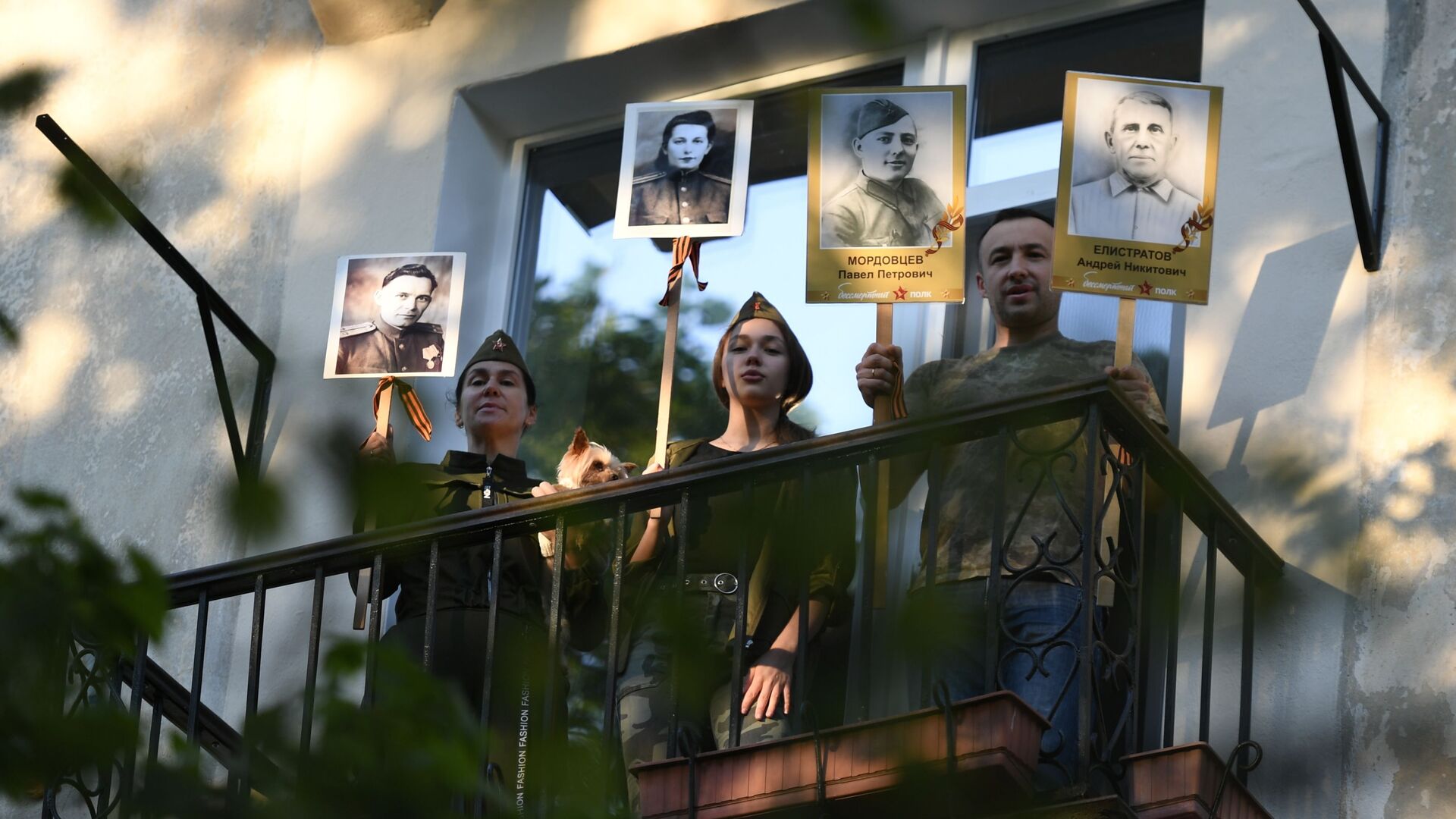 Жители дома с портретами родственников-фронтовиков поют песни на балконе в рамках всероссийской акции #ПоемДеньПобеды в Севастополе - اسپوتنیک افغانستان  , 1920, 06.05.2022