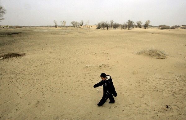 کودک در امتداد یک تپه ماسه ای در ویسی ، ولایت گانسو چین، جایی که کشاورزی  منجر به بیابان زایی شده است، قدم می زند. - اسپوتنیک افغانستان  