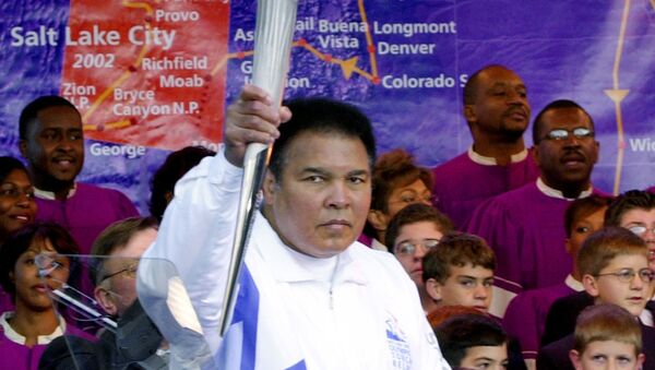 Boxing legend Muhammad Ali holds up the first Olympic torch lit from the cauldron in front of a map showing the torch's route during a ceremony at Centennial Olympic Park in Atlanta Tuesday, Dec. 4, 2001 - اسپوتنیک افغانستان  