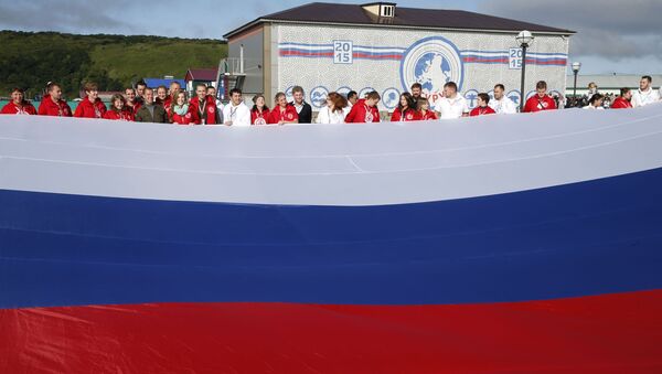 Председатель правительства РФ Дмитрий Медведев фотографируется с участниками всероссийского молодежного образовательного форума Итуруп на фоне флага России - اسپوتنیک افغانستان  