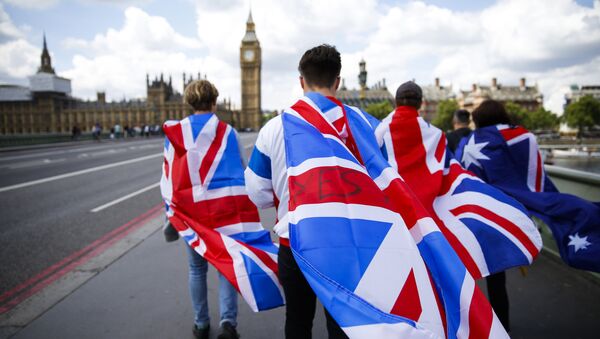 People walk over Westminster Bridge wrapped in Union flags, towards the Queen Elizabeth Tower (Big Ben) and The Houses of Parliament in central London on June 26, 2016 - اسپوتنیک افغانستان  