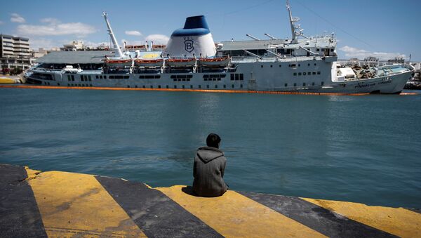 Мигрант напротив накренившегося списанного пассажирского парома Panagia Tinou в порту города Пирей в Греции - اسپوتنیک افغانستان  