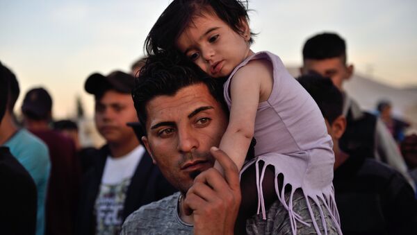 A man carries a child on his shoulders at the migrant and refugee makeshift camp near the village of Idomeni on the Greek-Macedonian border on April 16, 2016. - اسپوتنیک افغانستان  