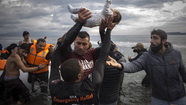 A volunteer holds up a baby as others help migrants and refugees to disembark from a dinghy after their arrival from the Turkish coast to the Greek island of Lesbos, Wednesday, Nov. 25, 2015. - اسپوتنیک افغانستان  