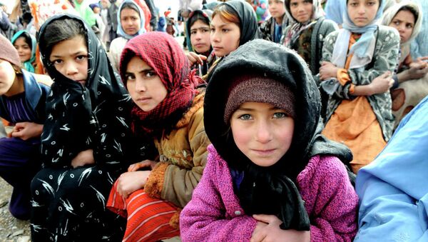 Village girls wait as humanitarians unload a shipment of food, clothing and supplies in western Afghanistan. - اسپوتنیک افغانستان  