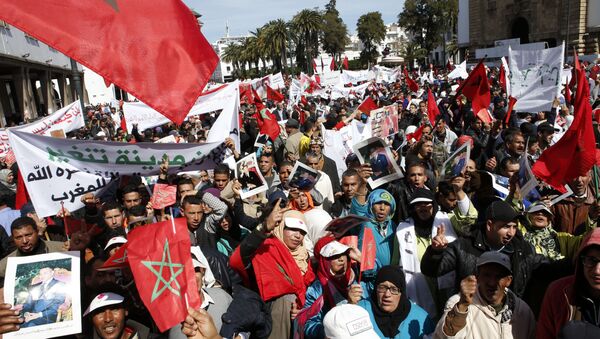 Protesters hold portraits of Morocco's King Mohammed VI and the Moroccan flag as they chant slogans during a rally, in Rabat, Morocco, Sunday, March 13, 2016. Morocco has accused U.N. Secretary-General Ban Ki-moon of abandoning neutrality, objectivity and impartiality during a recent visit to Western Saharan refugee camps in southern Algeria - اسپوتنیک افغانستان  