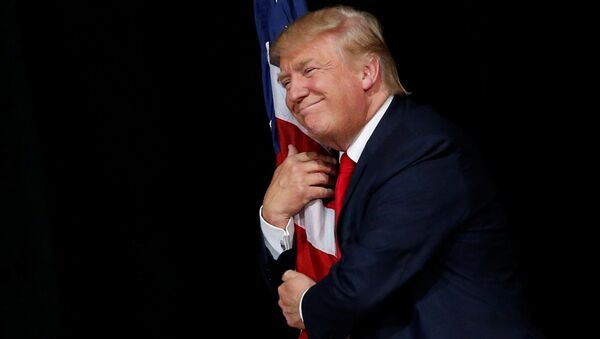 Donald Trump hugs a U.S. flag as he comes onstage to rally with supporters in Tampa, Florida, U.S. October 24, 2016 - اسپوتنیک افغانستان  